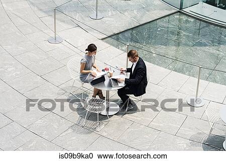 Stock Image - Young businesswoman and man meeting at sidewalk cafe, high angle view. Fotosearch