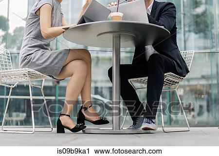 Stock Image - Young businesswoman and man meeting at sidewalk cafe, neck down view. Fotosearch