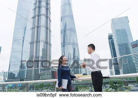 Young businesswoman and man talking in city financial district, Shanghai, China View Large Photo Image Stock Image - Young businesswoman and man talking in city financial district, Shanghai, China. Fotosearch