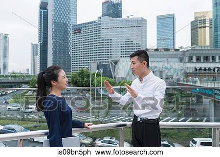 Young businesswoman and man talking on balcony in city financial district, Shanghai, China View Large Photo Image Stock Image - Young businesswoman and man talking on balcony in city financial district, Shanghai, China. Fotosearch