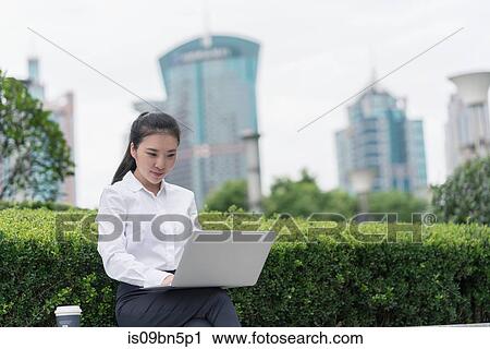 Young businesswoman typing on laptop in city financial district, Shanghai, China View Large Photo Image Stock Image - Young businesswoman typing on laptop in city financial district, Shanghai, China. Fotosearch
