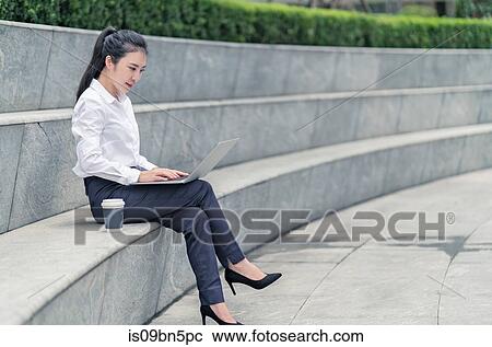 Young businesswoman typing on laptop on city seat, Shanghai, China View Large Photo Image Stock Image - Young businesswoman typing on laptop on city seat, Shanghai, China. Fotosearch