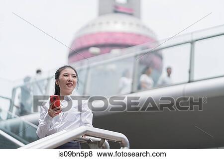 Young businesswoman with smartphone on city stairway, Shanghai, China View Large Photo Image Stock Photo - Young businesswoman with smartphone on city stairway, Shanghai, China. Fotosearch