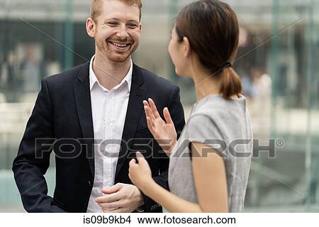 Picture - Young city businessman and woman having discussion outdoors. Fotosearch