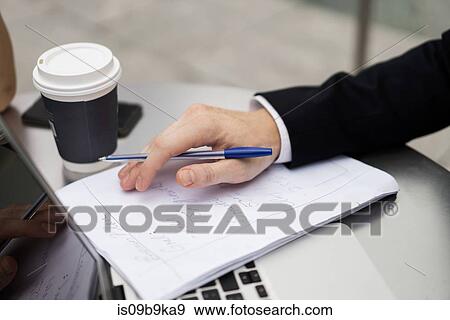 Young city businessman doing paperwork at sidewalk cafe, close up View Large Photo Image Stock Photo - Young city businessman doing paperwork at sidewalk cafe, close up. Fotosearch