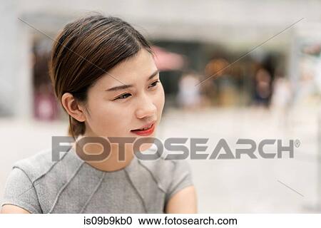 Stock Image - Young city businesswoman outdoors, head and shoulder. Fotosearch