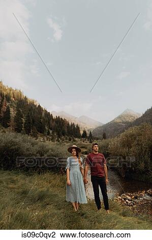 Stock Image - Young couple holding hands by rural river, portrait, Mineral King, California, USA. Fotosearch