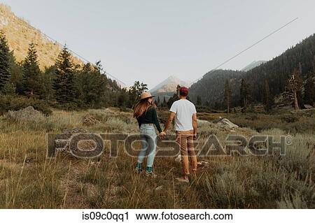 Stock Image - Young couple holding hands in rural valley, rear view, Mineral King, California, USA. Fotosearch