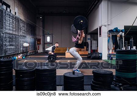 Young couple lifting barbell in gym View Large Photo Image Stock Photo - Young couple lifting barbell in gym. Fotosearch