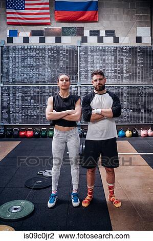 Young couple posing with arms crossed in gym View Large Photo Image Stock Image - Young couple posing with arms crossed in gym. Fotosearch