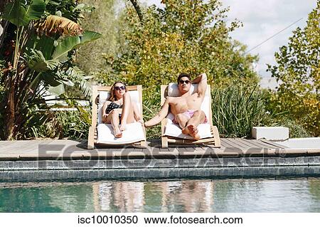 Young couple relaxing on deckchair by swimming pool View Large Photo Image Stock Image - Young couple relaxing on deckchair by swimming pool. Fotosearch
