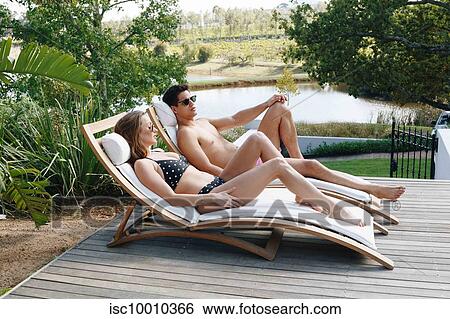 Young couple relaxing on deckchair by pond View Large Photo Image Stock Photograph - Young couple relaxing on deckchair by pond. Fotosearch