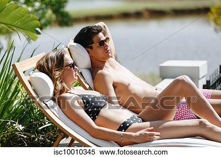 Young couple relaxing on deckchair by pond View Large Photo Image Stock Photography - Young couple relaxing on deckchair by pond. Fotosearch