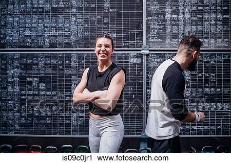 Young couple standing back to back in gym View Large Photo Image Stock Image - Young couple standing back to back in gym. Fotosearch