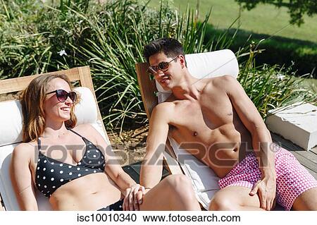 Stock Image - Young couple talking and relaxing on deckchair. Fotosearch