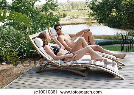 Young couple talking and relaxing on deckchair by pond View Large Photo Image Stock Image - Young couple talking and relaxing on deckchair by pond. Fotosearch