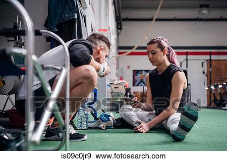 Young couple using smartphone in gym View Large Photo Image Stock Photo - Young couple using smartphone in gym. Fotosearch