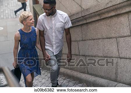 Young couple walking up steps, hand in hand, smiling View Large Photo Image Stock Image - Young couple walking up steps, hand in hand, smiling. Fotosearch