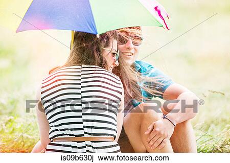Young couple with umbrella relaxing in field View Large Photo Image Stock Image - Young couple with umbrella relaxing in field. Fotosearch