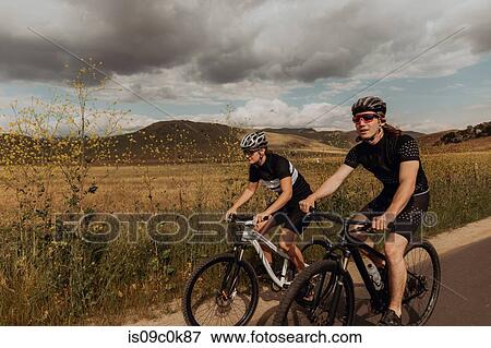 Young cycling couple cycling on rural road, Exeter, California, USA View Large Photo Image Stock Photo - Young cycling couple cycling on rural road, Exeter, California, USA. Fotosearch