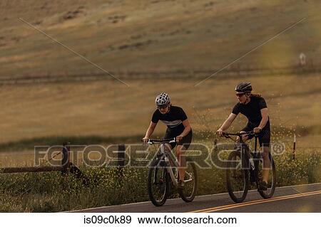 Young cycling couple cycling on rural road, Exeter, California, USA View Large Photo Image Stock Photo - Young cycling couple cycling on rural road, Exeter, California, USA. Fotosearch