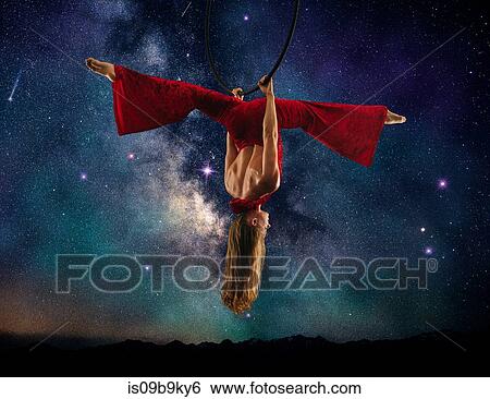 Young female aerial acrobat doing splits hanging upside down from hoop, milky way background View Large Photo Image Stock Photograph - Young female aerial acrobat doing splits hanging upside down from hoop, milky way background. Fotosearch