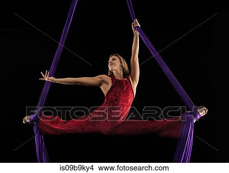 Young female aerial acrobat doing the splits with feet wrapped in silk rope against black background View Large Photo Image Picture - Young female aerial acrobat doing the splits with feet wrapped in silk rope against black background. Fotosearch