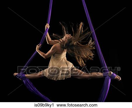 Young female aerial acrobat doing the splits with feet wrapped in silk rope against black background View Large Photo Image Stock Image - Young female aerial acrobat doing the splits with feet wrapped in silk rope against black background. Fotosearch
