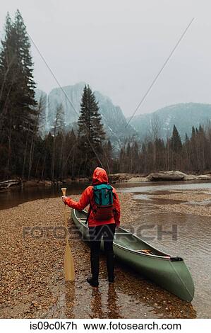 Stock Image - Young female canoeist preparing canoe in river, rear view, Yosemite Village, California, USA. Fotosearch