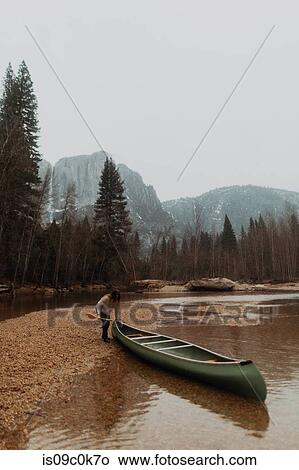 Young female canoeist pulling canoe from river, Yosemite Village, California, USA View Large Photo Image Picture - Young female canoeist pulling canoe from river, Yosemite Village, California, USA. Fotosearch