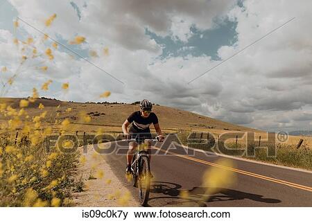 Young female cyclist cycling on rural road, Exeter, California, USA View Large Photo Image Stock Photo - Young female cyclist cycling on rural road, Exeter, California, USA. Fotosearch