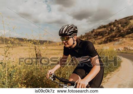Young female cyclist cycling on rural road, Exeter, California, USA View Large Photo Image Stock Photo - Young female cyclist cycling on rural road, Exeter, California, USA. Fotosearch