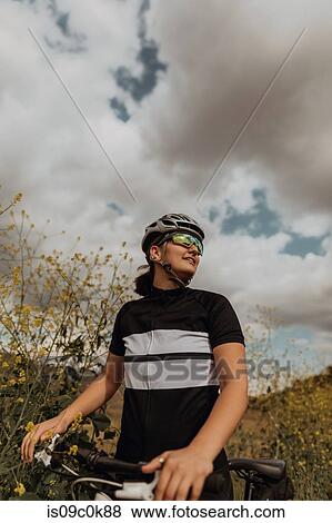 Stock Photo - Young female cyclist taking a break on roadside, Exeter, California, USA. Fotosearch