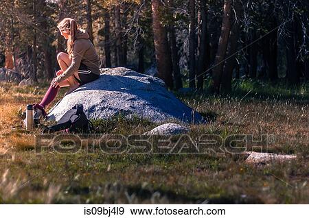 Young female hiker sitting on rock taking a break in Tuolumne Meadows, upper part of the Yosemite National Park, California, USA View Large Photo Image Stock Photo - Young female hiker sitting on rock taking a break in Tuolumne Meadows, upper part of the Yosemite National Park, California, USA. Fotosearch
