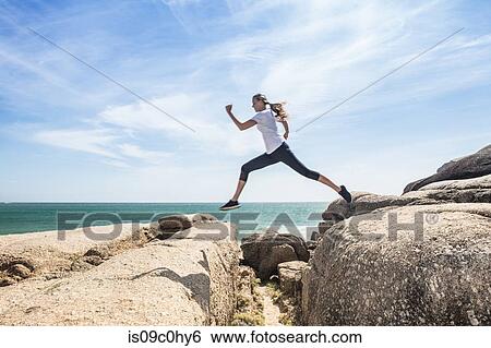 Young female runner leaping over beach rocks, full length, Cape Town, Western Cape, South Africa View Large Photo Image Stock Photograph - Young female runner leaping over beach rocks, full length, Cape Town, Western Cape, South Africa. Fotosearch