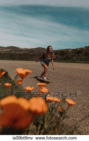 Young female skateboarder skateboarding along rural road, Jalama, California, USA View Large Photo Image Stock Photo - Young female skateboarder skateboarding along rural road, Jalama, California, USA. Fotosearch