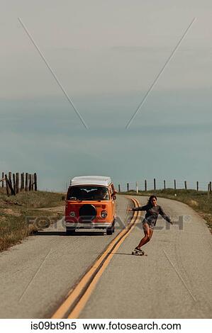 Young female skateboarder skateboarding down rural road, followed by recreational vehicle, Jalama, California, USA View Large Photo Image Stock Photography - Young female skateboarder skateboarding down rural road, followed by recreational vehicle, Jalama, California, USA. Fotosearch