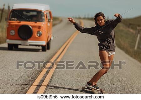 Young female skateboarder swerve skateboarding down rural road, followed by recreational vehicle, Jalama, California, USA View Large Photo Image Stock Photograph - Young female skateboarder swerve skateboarding down rural road, followed by recreational vehicle, Jalama, California, USA. Fotosearch