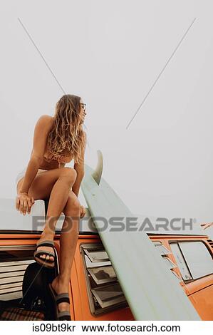 Young female surfer in bikini looking out from top of recreational vehicle at beach, Jalama, California, USA View Large Photo Image Stock Photography - Young female surfer in bikini looking out from top of recreational vehicle at beach, Jalama, California, USA. Fotosearch