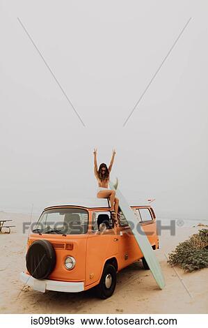 Young female surfer in bikini making victory sign from top of recreational vehicle at beach, Jalama, California, USA View Large Photo Image Stock Photograph - Young female surfer in bikini making victory sign from top of recreational vehicle at beach, Jalama, California, USA. Fotosearch