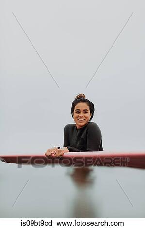 Young female surfer leaning on surfboard in calm misty sea, portrait, Ventura, California, USA View Large Photo Image Stock Image - Young female surfer leaning on surfboard in calm misty sea, portrait, Ventura, California, USA. Fotosearch