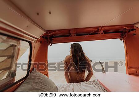 Stock Photo - Young female surfer looking out from recreational vehicle, rear view, Jalama, California, USA. Fotosearch