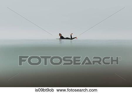 Young female surfer lying on surfboard in calm misty sea, full length portrait, Ventura, California, USA View Large Photo Image Stock Image - Young female surfer lying on surfboard in calm misty sea, full length portrait, Ventura, California, USA. Fotosearch