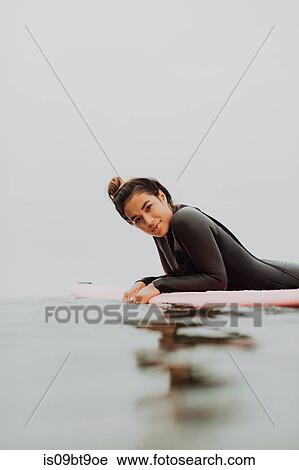 Young female surfer lying on surfboard in calm misty sea, portrait, Ventura, California, USA View Large Photo Image Stock Image - Young female surfer lying on surfboard in calm misty sea, portrait, Ventura, California, USA. Fotosearch