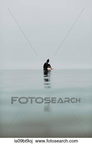 Young female surfer sitting on surfboard in calm misty sea, Ventura, California, USA View Large Photo Image Stock Image - Young female surfer sitting on surfboard in calm misty sea, Ventura, California, USA. Fotosearch