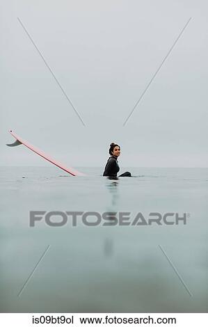 Young female surfer sitting on surfboard in calm misty sea, portrait, Ventura, California, USA View Large Photo Image Stock Image - Young female surfer sitting on surfboard in calm misty sea, portrait, Ventura, California, USA. Fotosearch