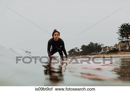Stock Image - Young female surfer surfing on misty calm sea, Ventura, California, USA. Fotosearch