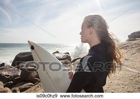 Young female surfer with flyaway hair looking out from beach rock, Cape Town, Western Cape, South Africa View Large Photo Image Stock Photo - Young female surfer with flyaway hair looking out from beach rock, Cape Town, Western Cape, South Africa. Fotosearch