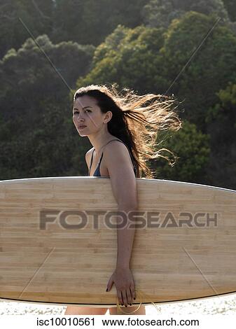 Young female surfer with long windswept hair carrying surfboard on beach, Victoria, Australia View Large Photo Image Stock Image - Young female surfer with long windswept hair carrying surfboard on beach, Victoria, Australia. Fotosearch