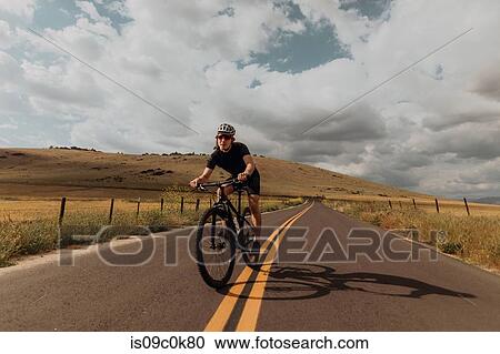 Stock Image - Young male cyclist cycling on rural road, Exeter, California, USA. Fotosearch
